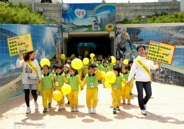 증평지역 어린이 안전 걷기대회에서 어린이들이 안전을 상징하는 노란색깔의 옷을 입고 보강천 미루나무 숲까지 걸어가고 있다.